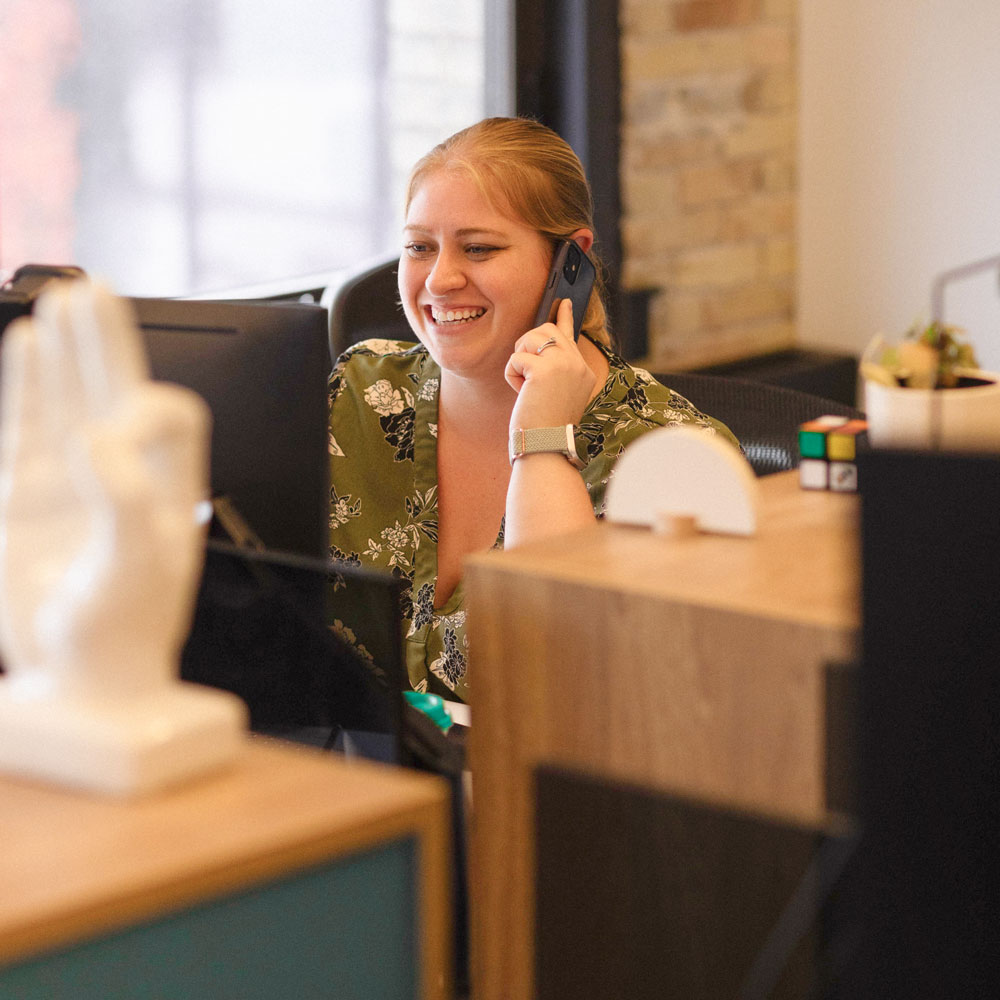 Brittany in the office talking on phone with a smile on her face